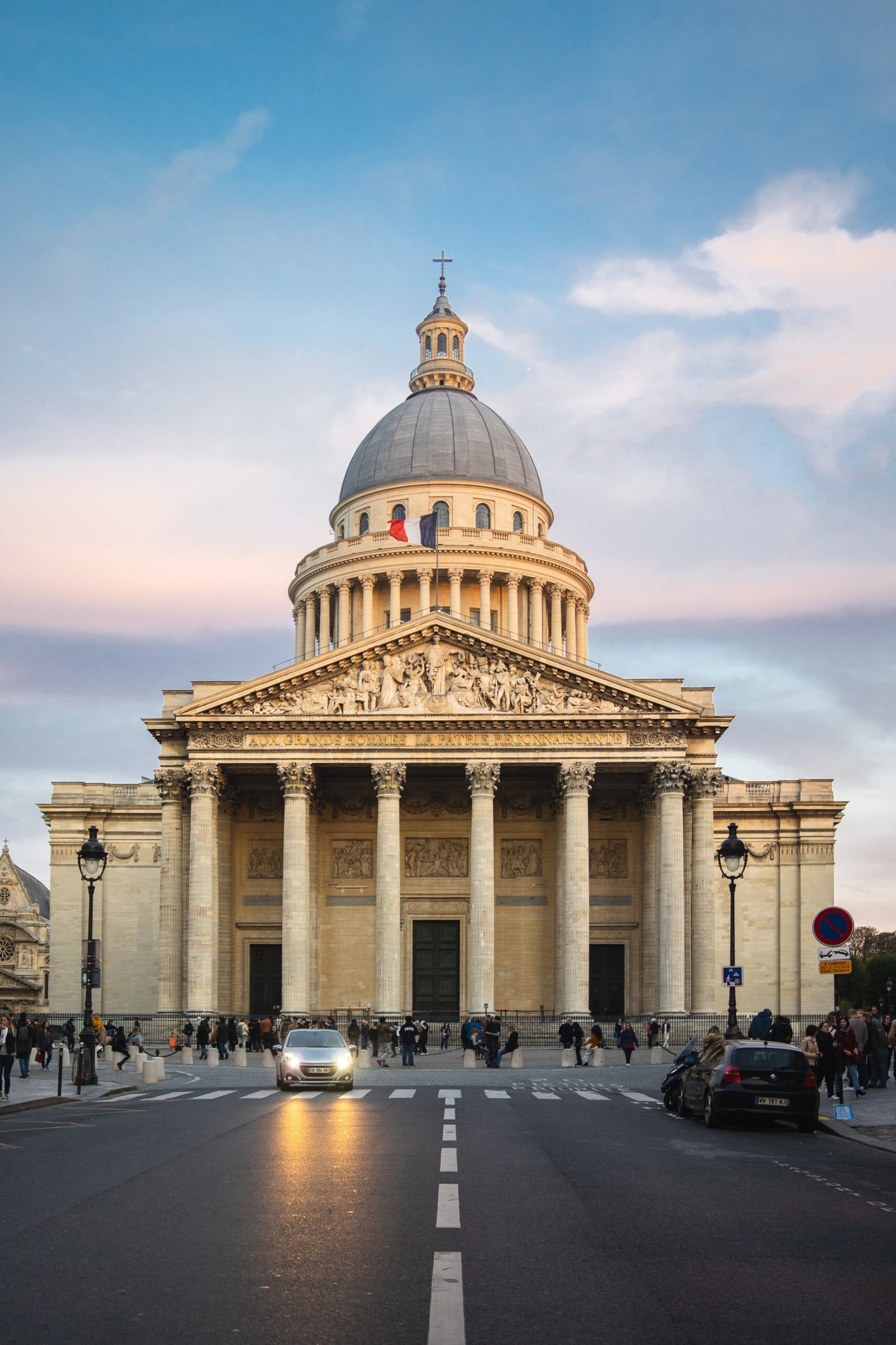 The Pantheon surrounded by people under a cloudy sky during sunset in Paris in France